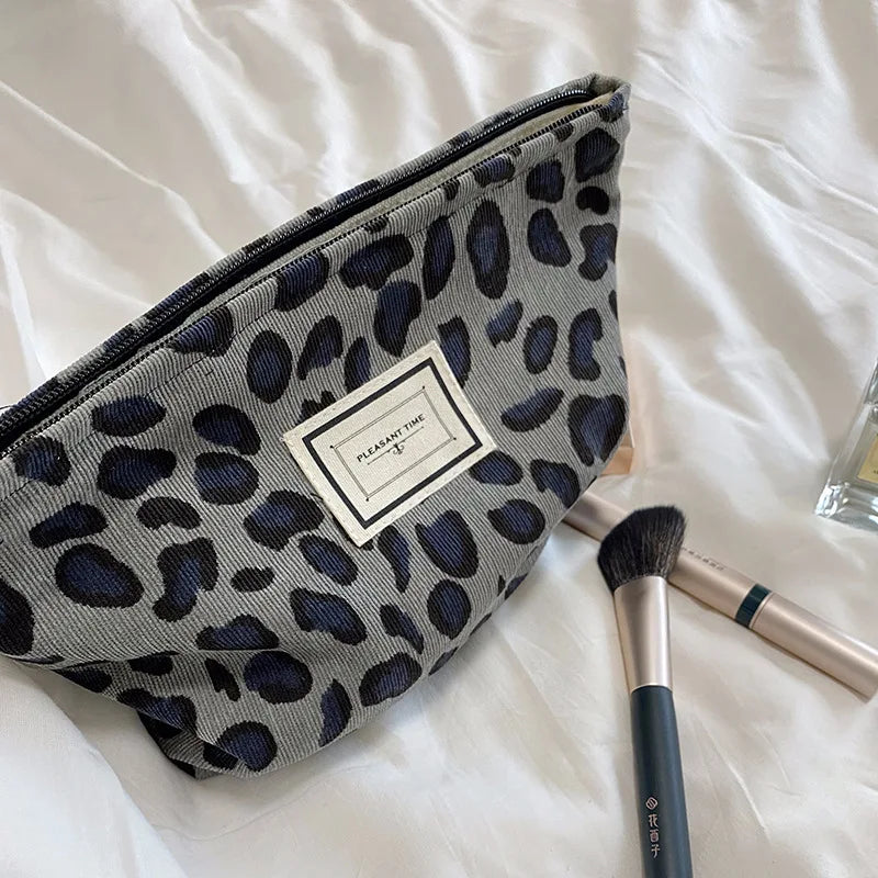 Leopard print makeup bag with brushes on a white surface