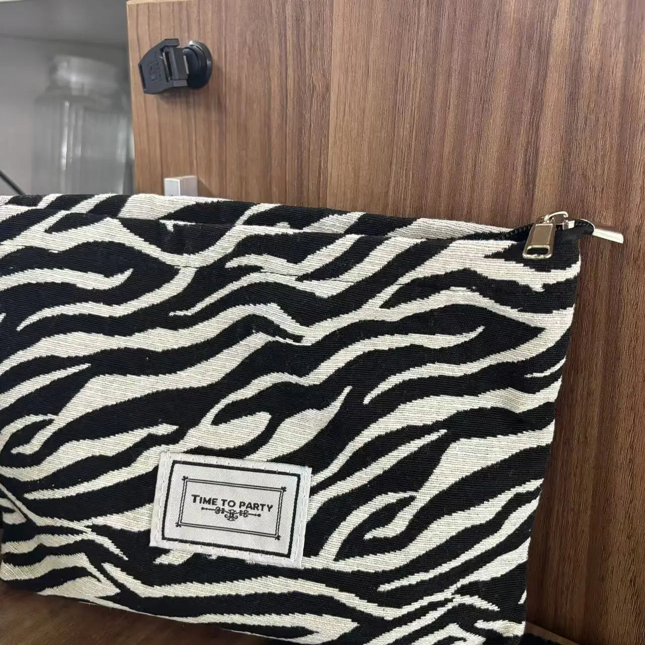 Zebra patterned pouch with 'Time to Party' label on a wooden surface