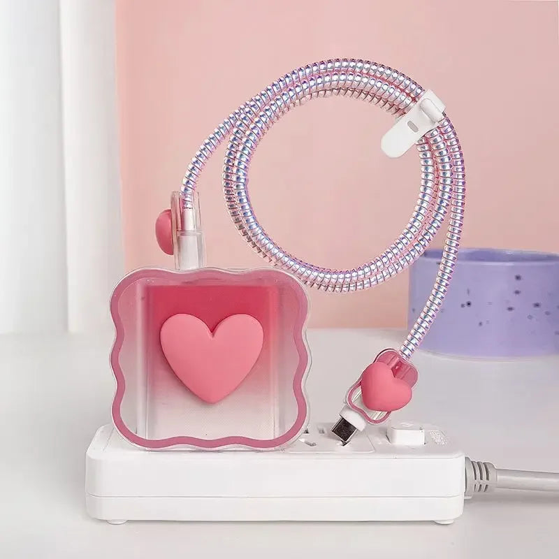 Pink heart-shaped charger head protective sleeve with a coiled cable on a white surface.