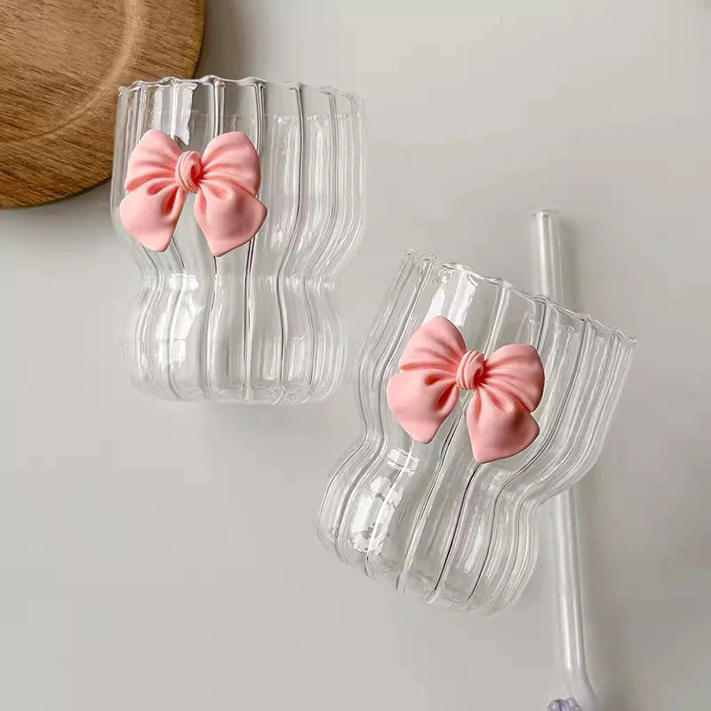 Clear glasses with pink bow decorations on a light gray background