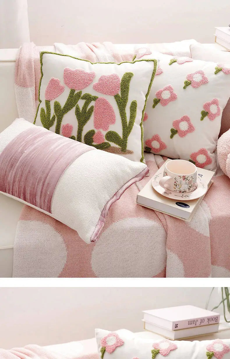 Floral patterned cushions on a sofa with a cup and saucer.