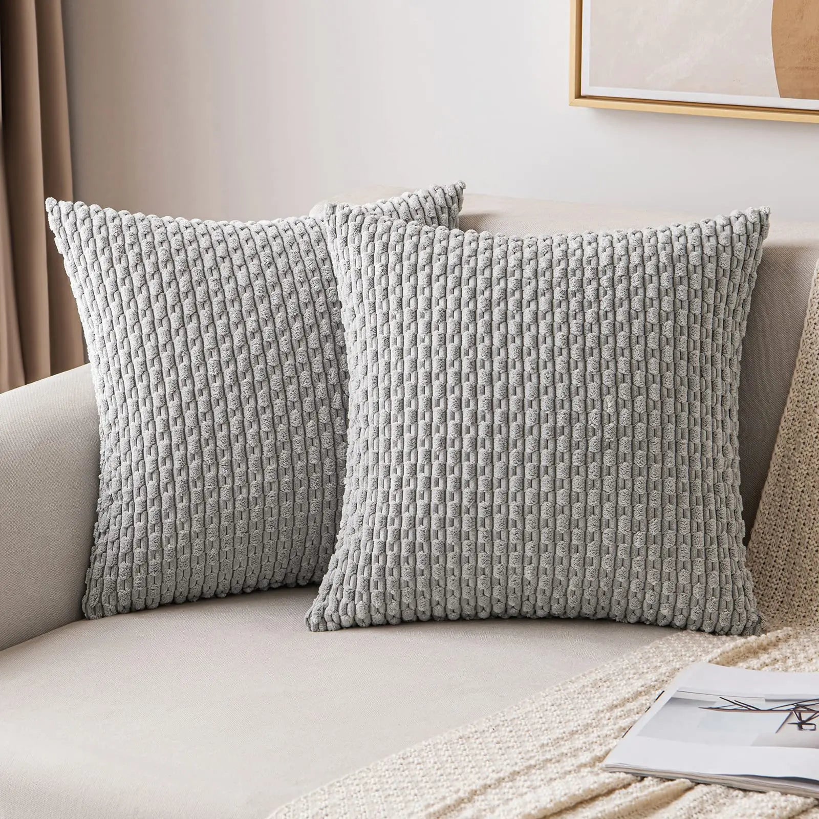 Two textured gray pillows on a beige sofa with a neutral background