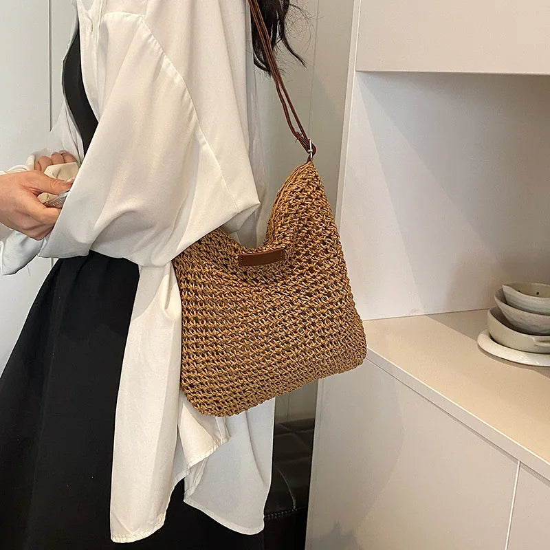 Person wearing a white shirt with a brown woven handbag in a minimalistic setting.